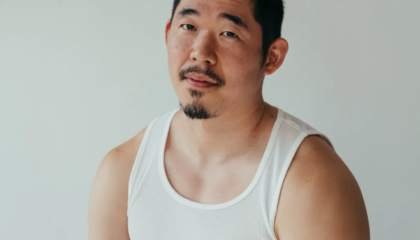 Asian American man (poet Jimin Seo) looks at camera, wearing a white A T-Shirt and black pants