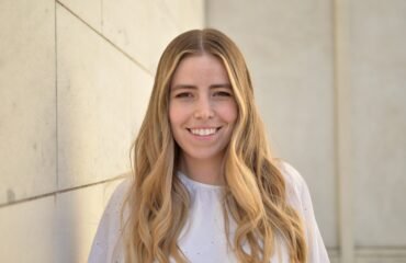 Blonde woman (poet Maria Zoccola) wearing white blouse smiling and facing camera directly