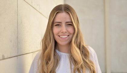 Blonde woman (poet Maria Zoccola) wearing white blouse smiling and facing camera directly