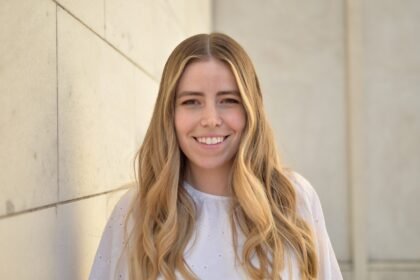 Blonde woman (poet Maria Zoccola) wearing white blouse smiling and facing camera directly