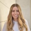 Blonde woman (poet Maria Zoccola) wearing white blouse smiling and facing camera directly