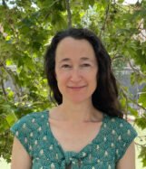 Woman in green spotted top (Rachel Trousdale) looks at the camera