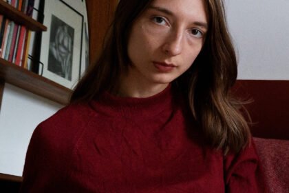 Nasim Luczaj Brunette woman (Nasim Luczaj) in red top looks at camera.