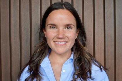 Liza Hudock by Michelle Getzen Portrait of woman with brown hair, in a blue collared shirt, smiling at the camera.