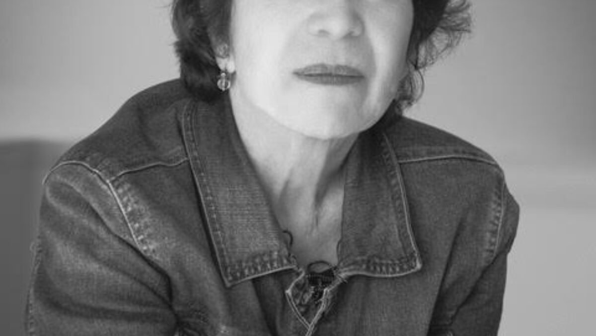 Black and white photo of a woman with short, dark curly hair, staring into the camera.