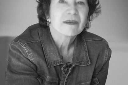 Black and white photo of a woman with short, dark curly hair, staring into the camera.