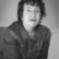 Black and white photo of a woman with short, dark curly hair, staring into the camera.