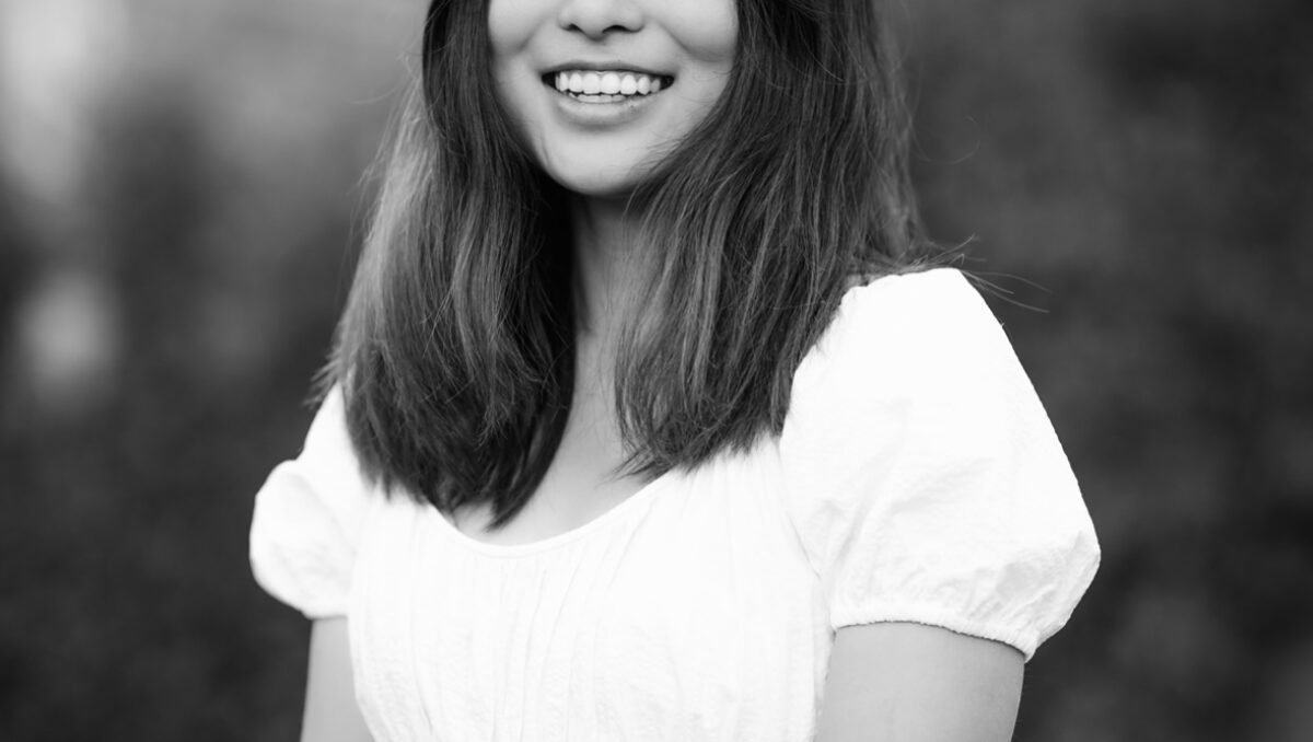 Allison Zhang Black and white photo of an Asian woman in white top, smiling at camera.