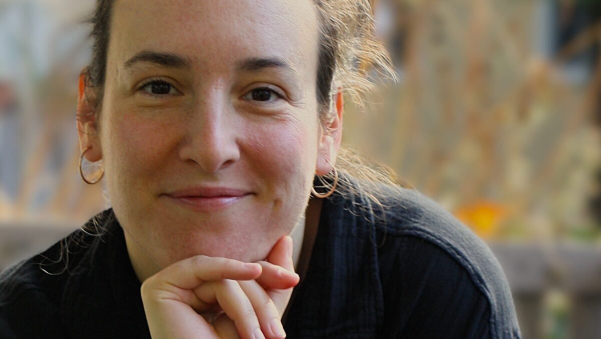 karla_hirsch White woman stares directly in the camera, chin on her hand.