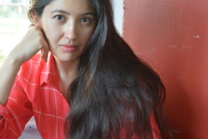 Woman in a red dress stares at the camera